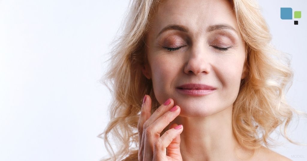 Model image of a mature woman touching her jaw.